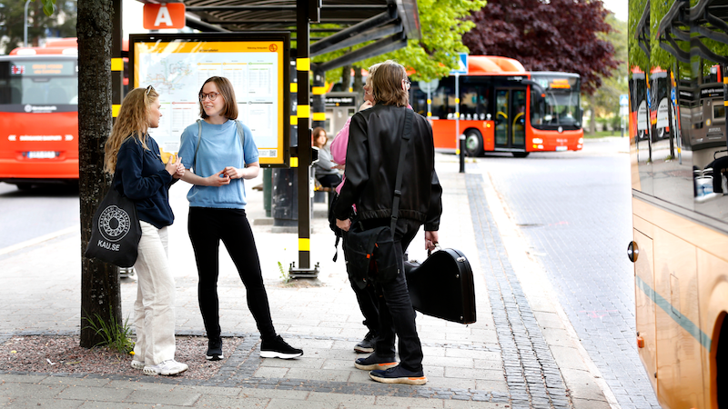 Tre personer som väntar på bussen vid Karlstads universitet