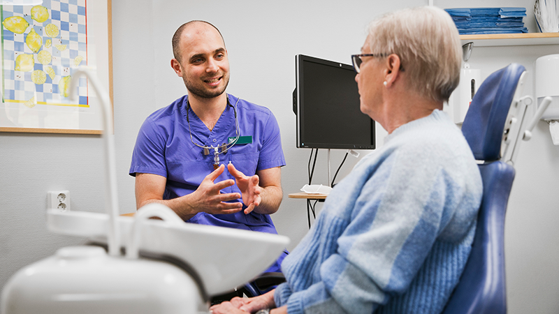 Behandlare pratar med patient i stol