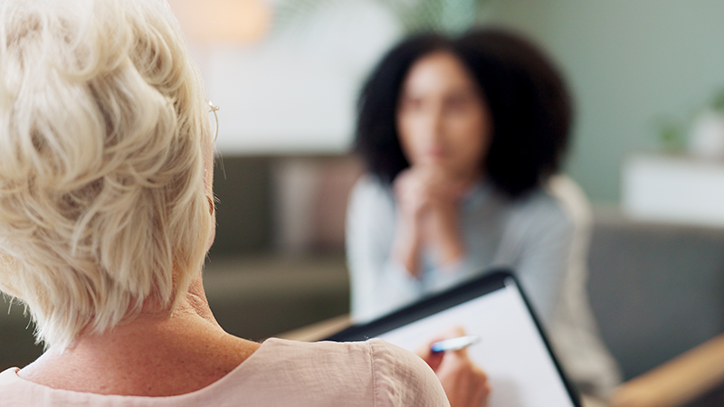 Terapeut gör anteckningar med patient i bakgrunden