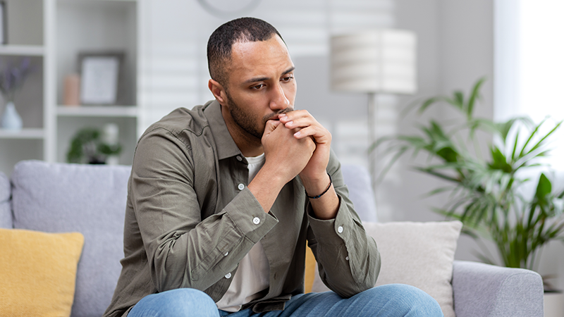 orolig man sitter i soffan