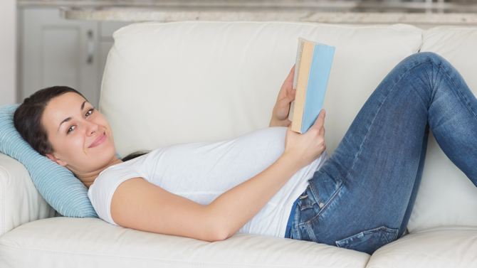 gravid kvinna ligger och läser i soffan
