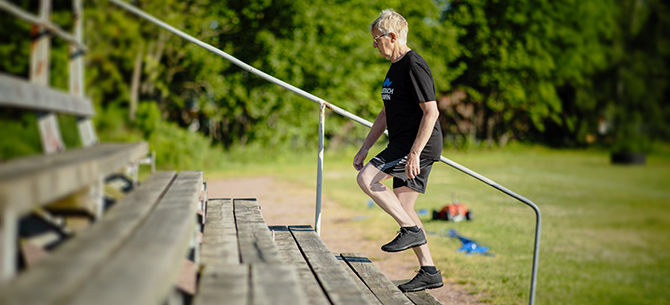 Bild på äldre man som går i en trappa, en utomhusläktare på en idrottsarena