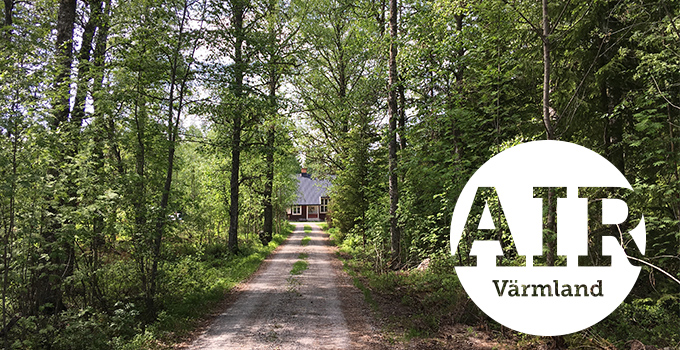 En stig som leder till en stuga som skymtar i horisonten är omringad av lövskog. Till höger i bilden finns ett cirkulärt grafiskt element med texten AIR Värmland.