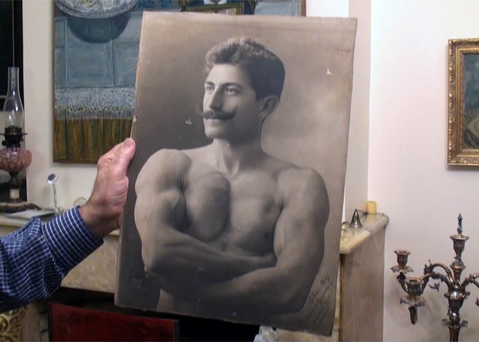 Någon håller upp ett svartvitt porträttfoto från tidigt 1900-tal. Fotot föreställer den osmanska officeren Selim Sirri Tarcan.