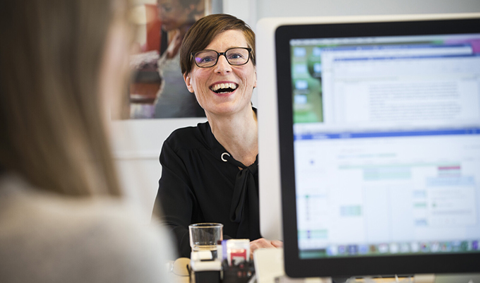 Medarbetare tittar fram bakom en datorskärm.