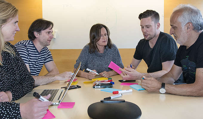 Medarbetare sitter vid skrivbord och skriver på postit-lappar.