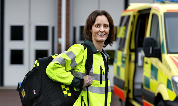 Ambulanspersonal med ryggsäck utanför en ambulans.