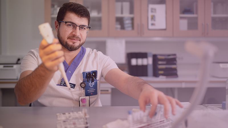 Man i ett laboratorium, fyller provrör.