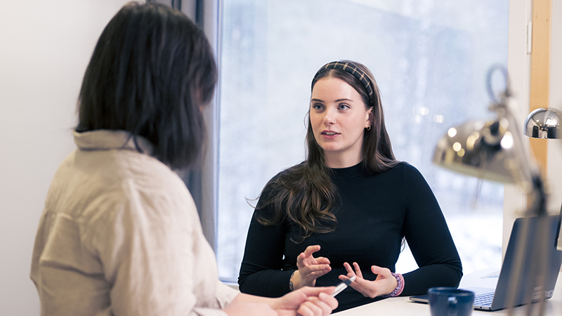 Två personer samtalar framför en dator. 