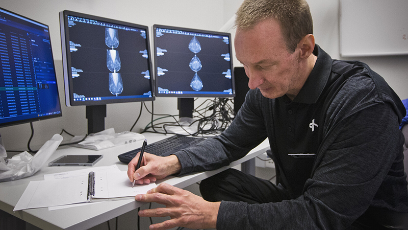 Man antecknar framför tre skärmar med röntgenbilder på.