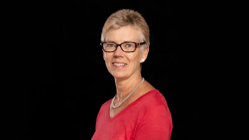 Korthårig kvinna med glasögon klädd i rött.