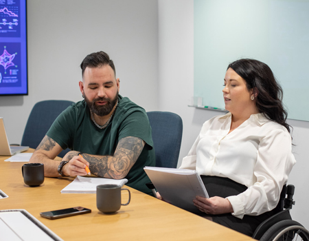Två personer med kaffekoppar vid ett konferensbord.