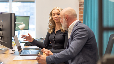 Kvinna och man vid skrivbord med dator.