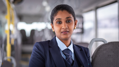 Kvinnlig busschaufför med kostym och slips i buss.