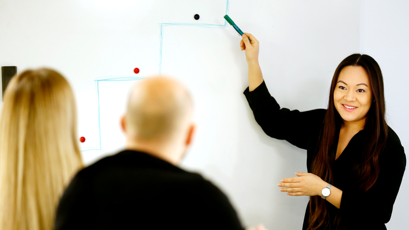 En kvinna pekar på en whiteboard. 