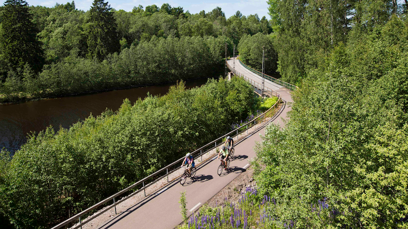 Tre personer som cyklar på Klarälvsbanan det är många gröna träd i bakgrunden 