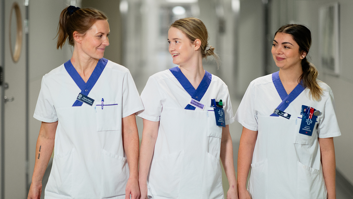 Tre sjuksköterskor går i rad i en korridor.