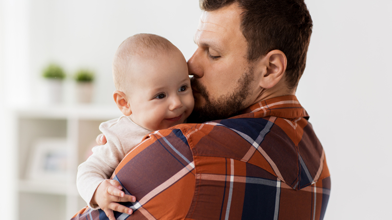 en man håller sin bäbis i famnen