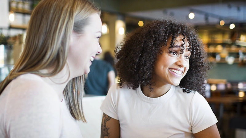Två tjejer umgås på ett café. 