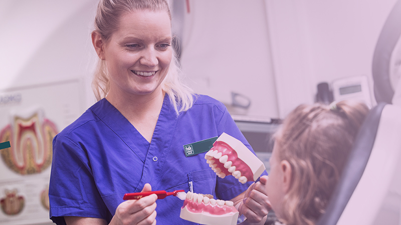 Kvinna borstar tänderna på en lösgom.