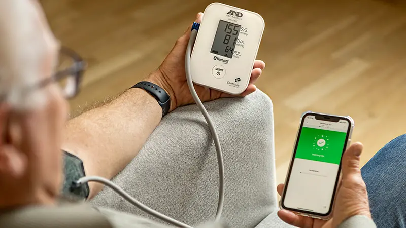 Foto som visar en person i hemmiljö genomföra en blodtrycksmätning.