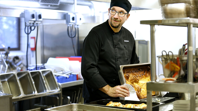 En kock i häller upp mat.