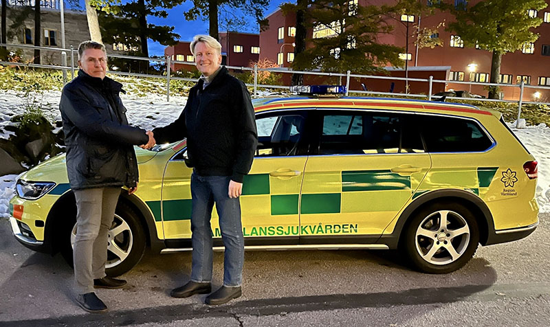 Politiker skakar hand framför en bil