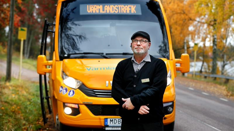 Förare står framför gult servicelinjefordon