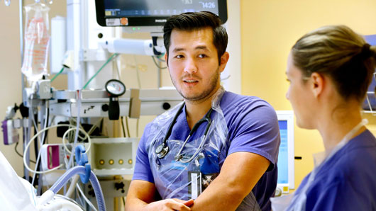 Mörkhyad manlig skötare och ljushyad kvinnlig sköterska.