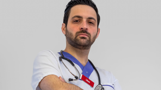 Man i sjukvårdskläder med armarna i kors, bestämd min.