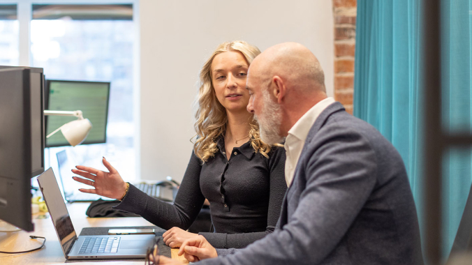 Kvinna och man i samtal vid dator.