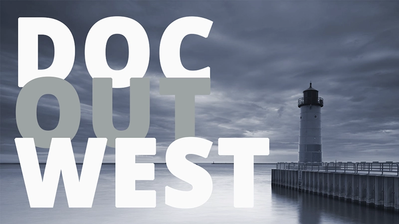 En grå himmel, vatten och en fyr. Texten Doc out west.