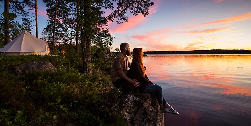 Ett par tittar på solnedgången vid sjö.