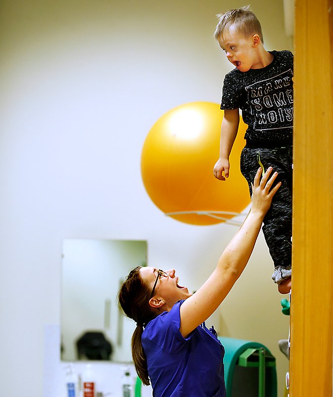 Barnrehabilitering - pojke i ribbstol och teraput under