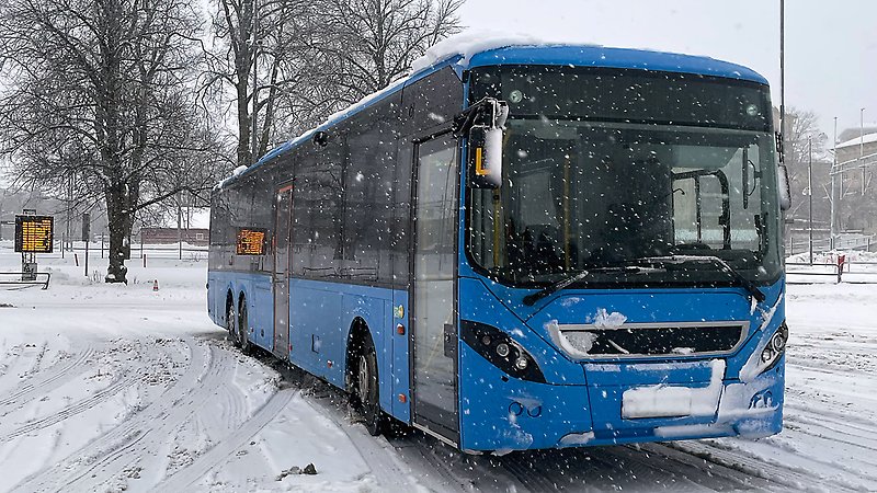 Blå buss i en snöig miljö.