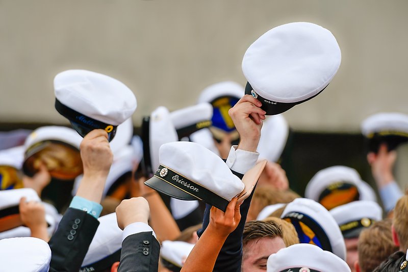 Studenter som firar och håller upp sina studentmössor i luften