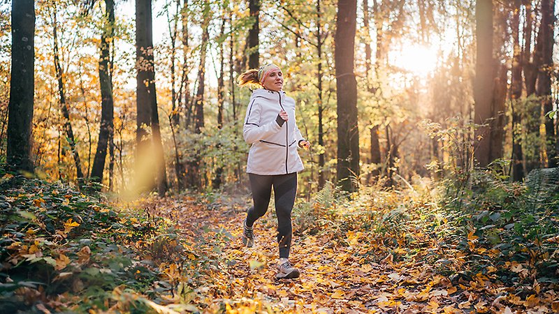 En kvinna joggar i en skog.