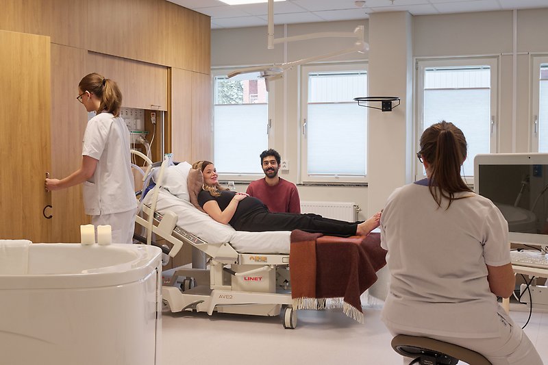 Gravid kvinna och en man tillsammans med två vårpersonal.