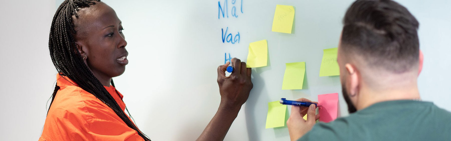 Kvinna och man med post-it på whiteboard.