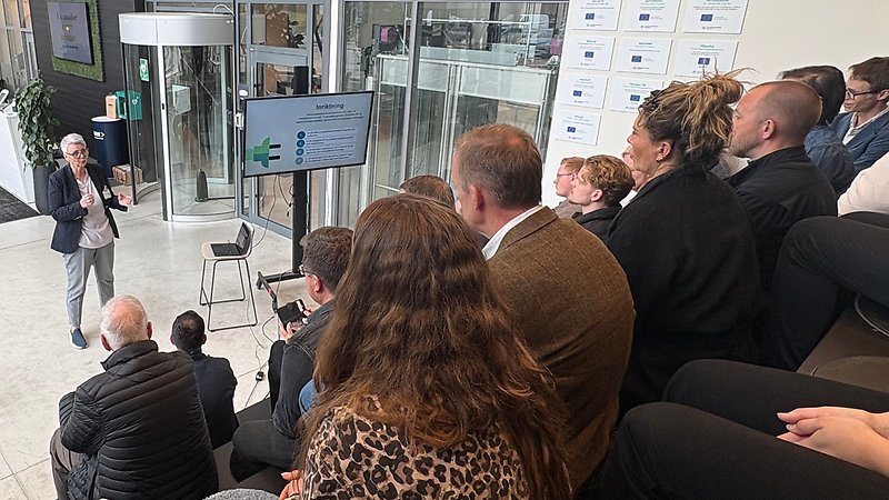 En kvinna står framför en grupp människor.